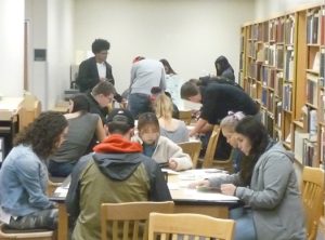 Several students study papers in the MASC reading room, sitting at different tables